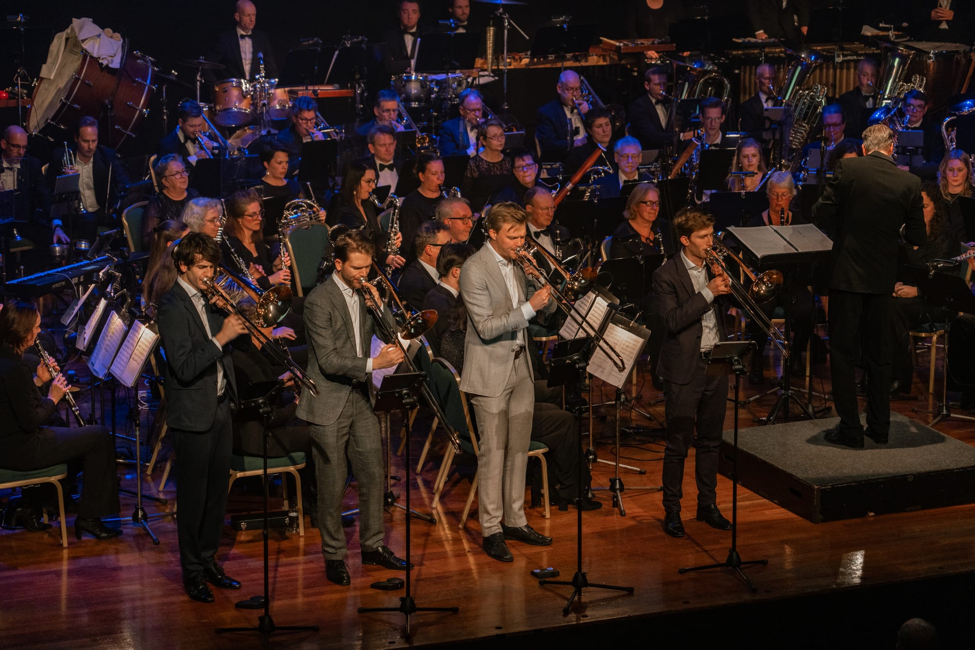 de vier trombonisten van het Nympheas Trombone Quartet met het orkest op de achtergrond